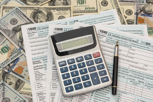tax forms 1040 with dollars and calculator for filling in April