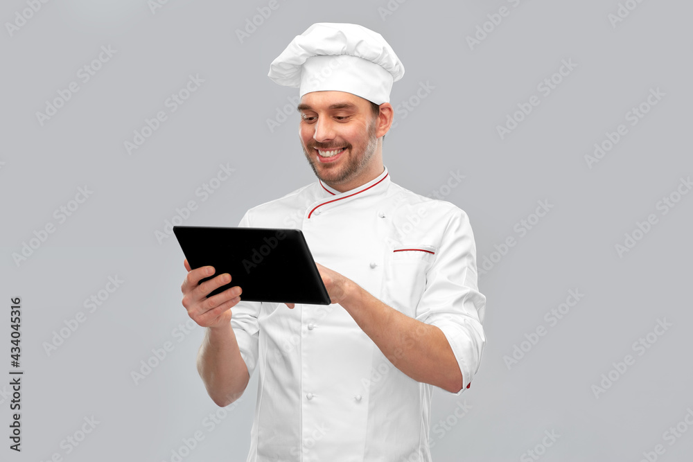 cooking, culinary and people concept - happy smiling male chef in toque with tablet pc computer over grey background cooking, culinary and people concept - happy smiling male chef in toque with tablet pc computer over grey background