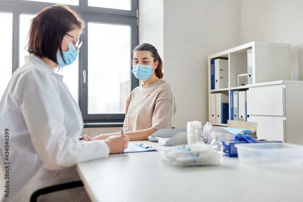 Obraz premium medicine, healthcare and pandemic concept - female doctor in medical protective mask or nurse with clipboard and patient at hospital