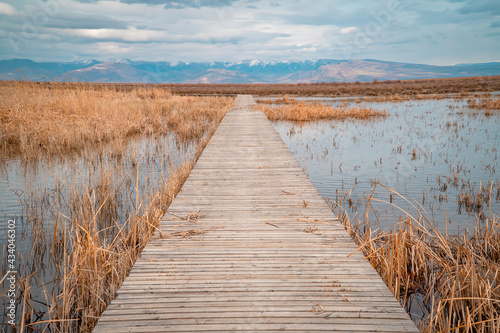 Moody panorama shot of a wooden bridge through landscapes with marshes and lakes inside Sultan Reedy (Sultansazligi) National Park, Central Anatolia, Turkey