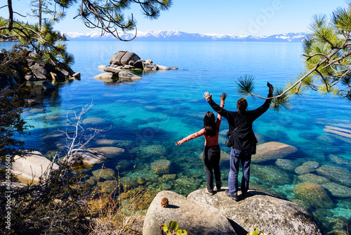 Happy couple with arms raised admiring view of Lake Tahoe, Achieving their hinking to see Bonsai Rock, Summer in California photo