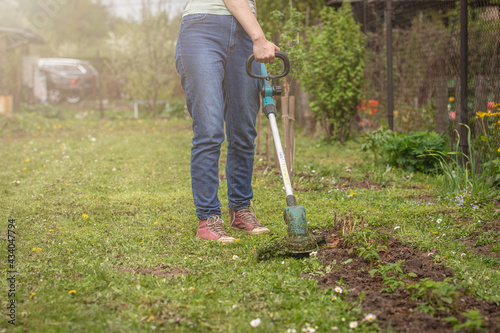 Woman mows the grass with a grass trimmer. Hobby and gardening. Yard and improvement
