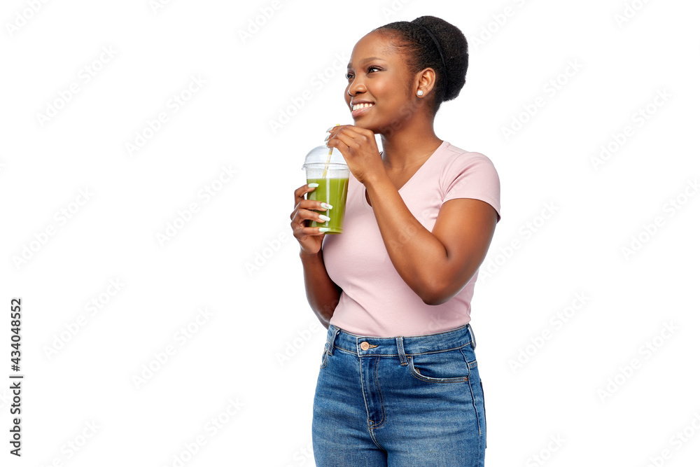 diet, healthy eating and detox concept - happy smiling young african american woman drinking green vegetable juice or smoothie from plastic cup with paper straw over white background diet, healthy eating and detox concept - happy smiling young african american woman drinking green vegetable juice or smoothie from plastic cup with paper straw over white background