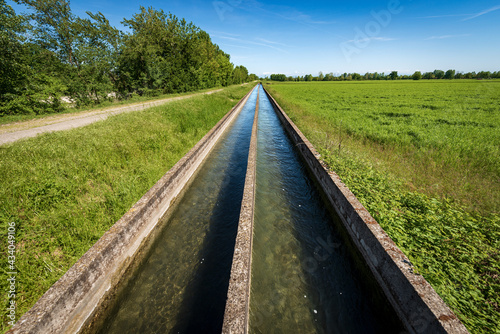 Two small concrete irrigation canals in the countryside, Padan Plain or Po valley (Pianura Padana, Italian). Mantua province, Italy, southern Europe.