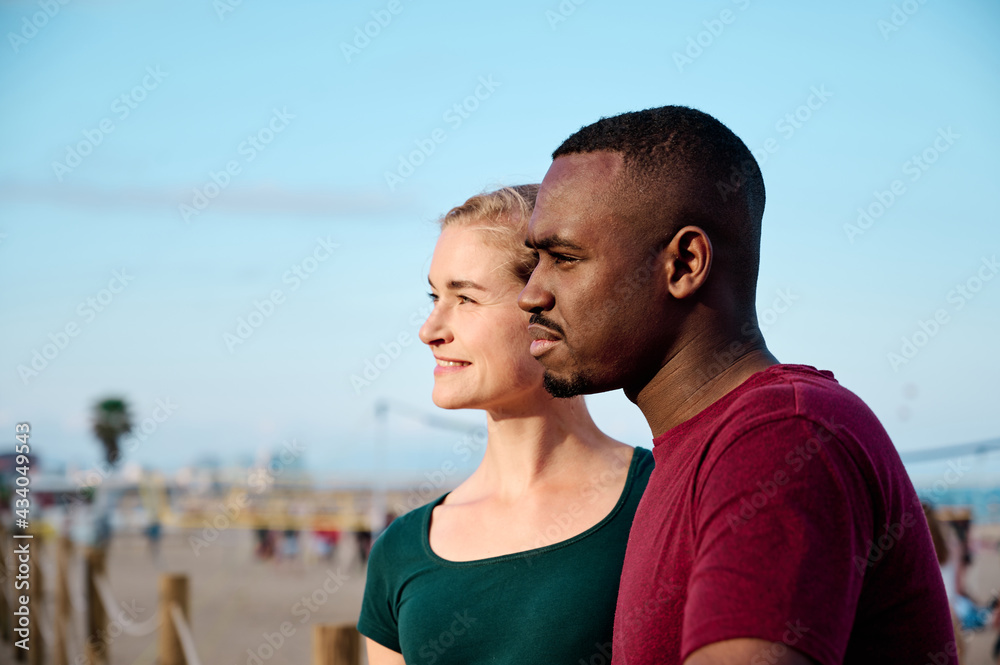 young multiethnic couple at the beach looking out of camera with copy space young multiethnic couple at the beach looking out of camera with copy space