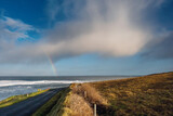 Colorful rainbow over Atlantic ocean, Mullaghmore, county Sligo, Ireland. Blue cloudy sky. Small road by the ocean