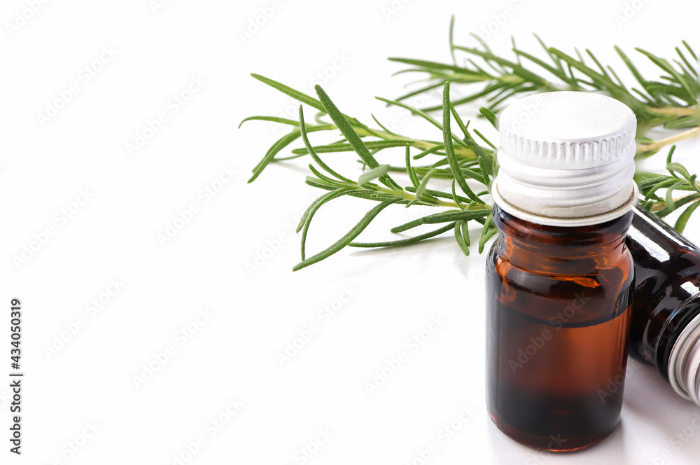Rosemary essential oil bottle with rosemary herb bunch on white background. Rosemary essential oil bottle with rosemary herb bunch on white background.