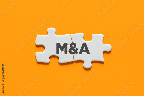 Connected puzzle pieces with the acronym M&A. Merger and acquisition in business photo