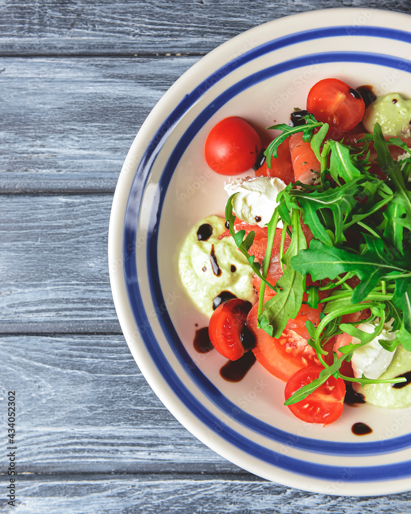 Salad with tomatoes and mozzarella topped with fresh arugula. Italian cuisine concept. Salad served in a white plate.