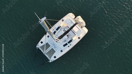 Aerial view of anchored sailing catamaran with beautiful perspective from the top of the mast. Silhouette of a boat from above.