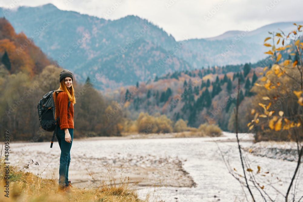 woman on the river bank in the mountains in the autumn forest in nature back view woman on the river bank in the mountains in the autumn forest in nature back view