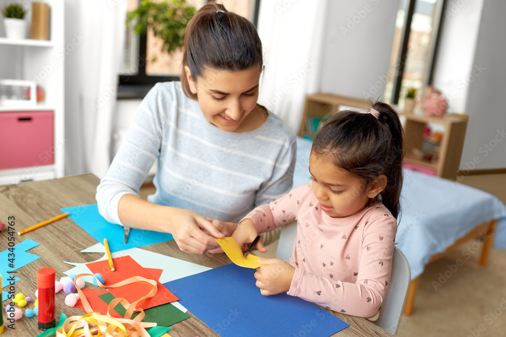 family, art and craft concept - mother spending time with her little daughter with glue making applique of color paper at home family, art and craft concept - mother spending time with her little daughter with glue making applique of color paper at home
