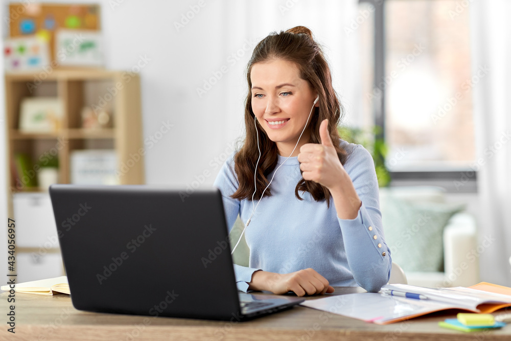 distant education, remote job and people concept - happy smiling female teacher with laptop computer and earphones having online class or video call at home office
