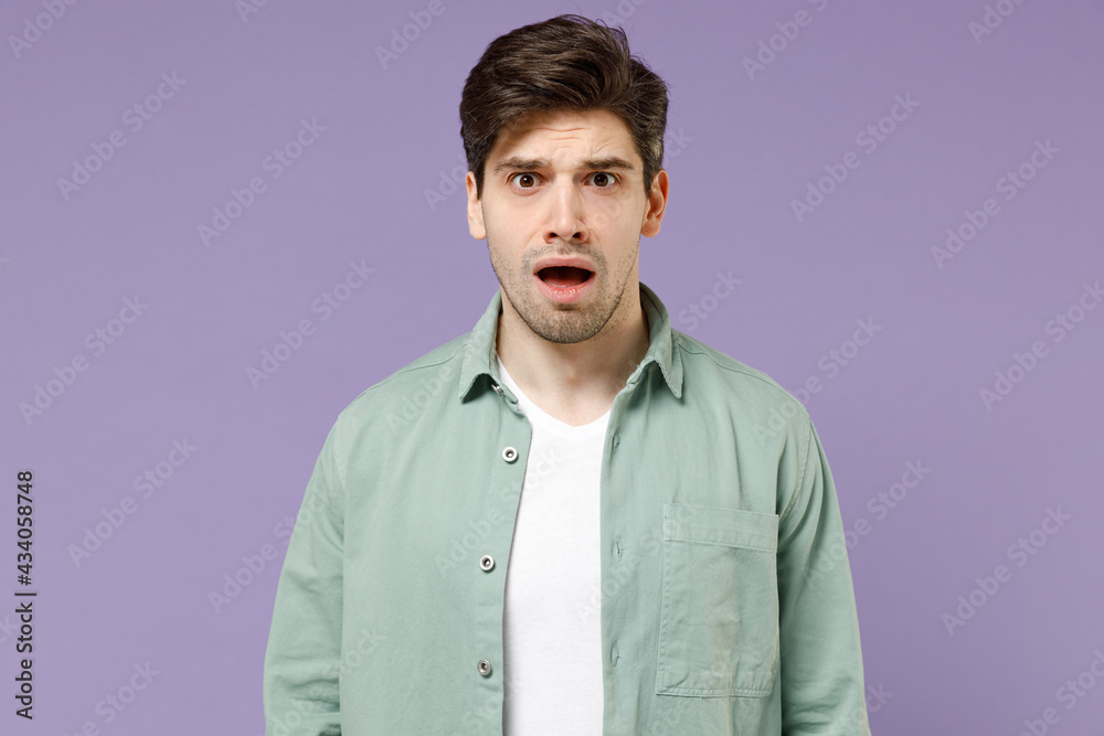 Young shocked amazed sad confused caucasian man 20s wearing casual mint shirt white t-shirt look camera with open mouth isolated on purple violet background studio portrait. People lifestyle concept Young shocked amazed sad confused caucasian man 20s wearing casual mint shirt white t-shirt look camera with open mouth isolated on purple violet background studio portrait. People lifestyle concept