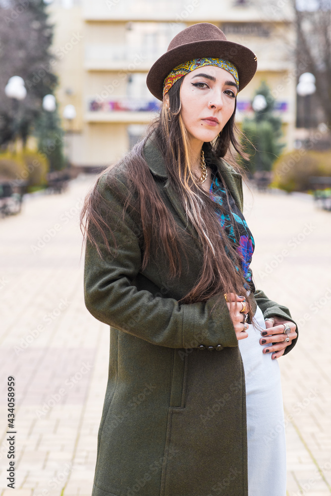 Portrait of a beautiful and stylish hippie girl in a hat on the street