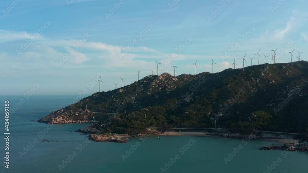 Wind generators farm on top of seaside mountain ridge on sunny day Wind generators farm on top of seaside mountain ridge on sunny day