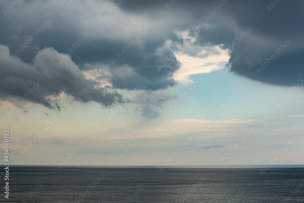 Attractive dramatic pink and gray clouds on azure blue sky over dark sea water surface. Beautiful natural contrast colors, high dynamic range. Storm, raining weather forecast. Nephology, meteorology.