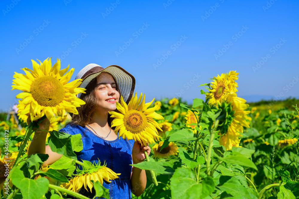 Piece of nature. cheerful child in straw hat among yellow flowers. small girl in summer sunflower field. happy childrens day. childhood happiness. portrait of happy kid with beautiful sunflower Piece of nature. cheerful child in straw hat among yellow flowers. small girl in summer sunflower field. happy childrens day. childhood happiness. portrait of happy kid with beautiful sunflower