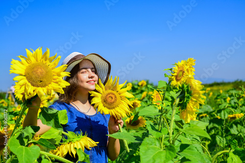Piece of nature. cheerful child in straw hat among yellow flowers. small girl in summer sunflower field. happy childrens day. childhood happiness. portrait of happy kid with beautiful sunflower