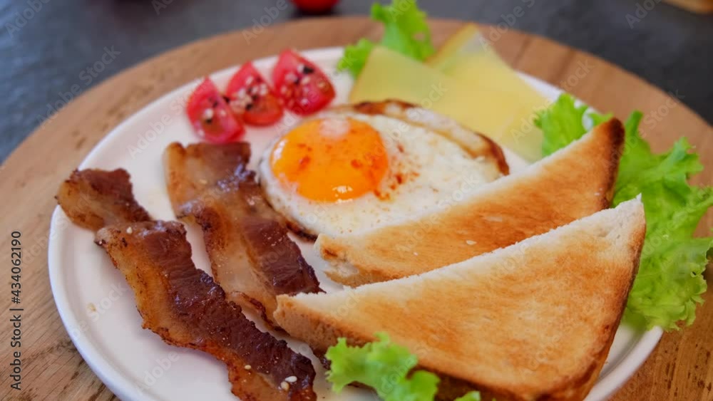 fried bacon with eggs, toasts, cherry tomatoes, and cheese on a white plate. tasty breakfast fried bacon with eggs, toasts, cherry tomatoes, and cheese on a white plate. tasty breakfast