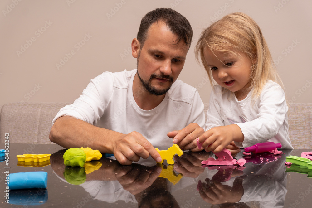 Father plays with child with colorful animals made from playdough, happy caucasian family time together, dad and daughter relationship, indoor activity with children. Father plays with child with colorful animals made from playdough, happy caucasian family time together, dad and daughter relationship, indoor activity with children.