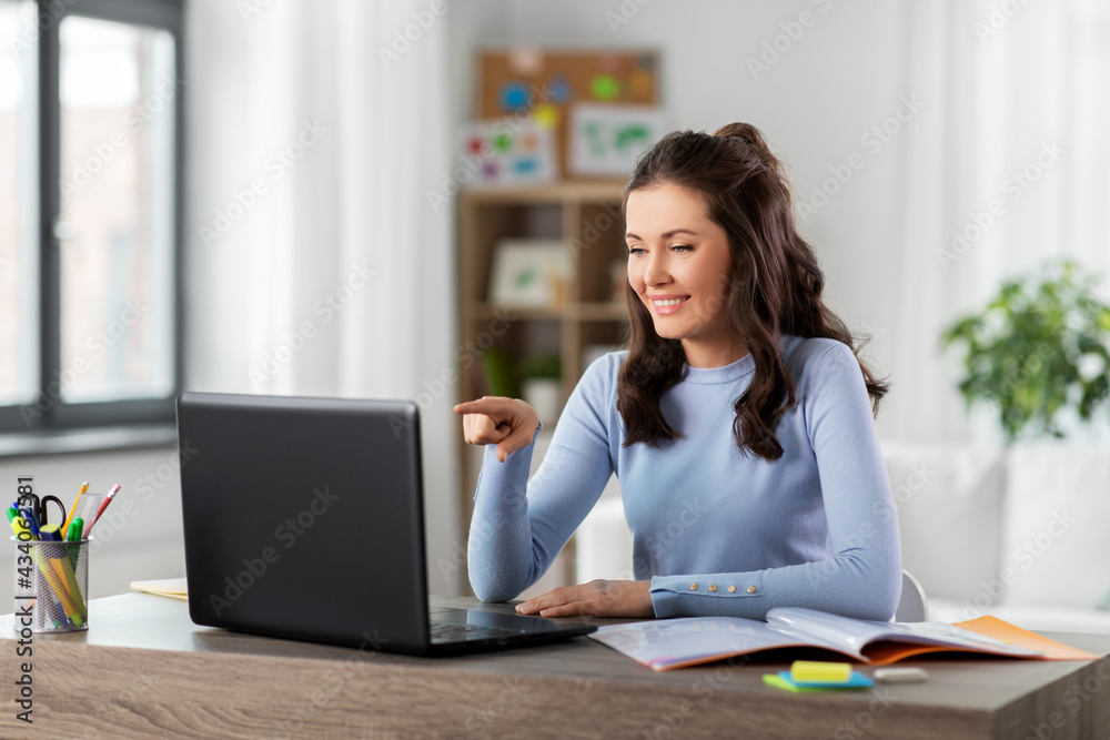 distant education, remote job and people concept - happy smiling female teacher with laptop computer having online class or video call at home office distant education, remote job and people concept - happy smiling female teacher with laptop computer having online class or video call at home office
