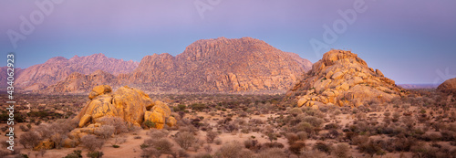 Panoramic image of a landscape in the blue hour just before sunrise with strongly eroded bare granite hills in the Erongo mountains, central Namibia © Chris