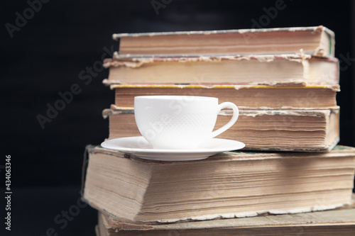 Stack book and cup of coffee on the black background.