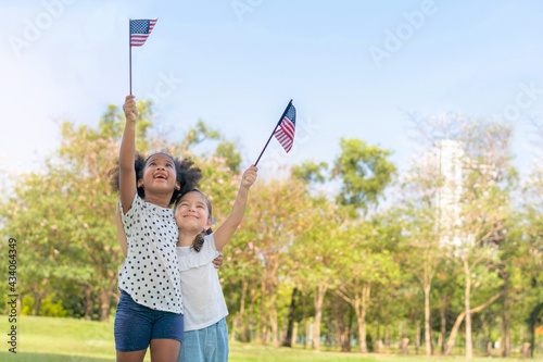 African american and caucasian mix girls smiling and raise a american flag at outdoors park, Ethnic girls , Relationship little kids, Diverse ethnic concept.