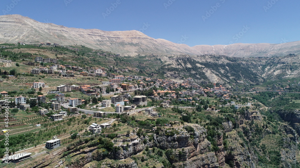 Obraz premium Lebanese village near the valley. Aerial 4k footage of the city and valley. Best hiking trails. Middle East country. Summer vacation in Lebanon. Village from bird's eye view. City landscape view