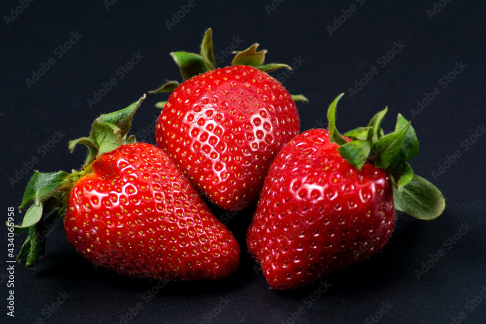 Three juicy large strawberries on a black background. Three juicy large strawberries on a black background.