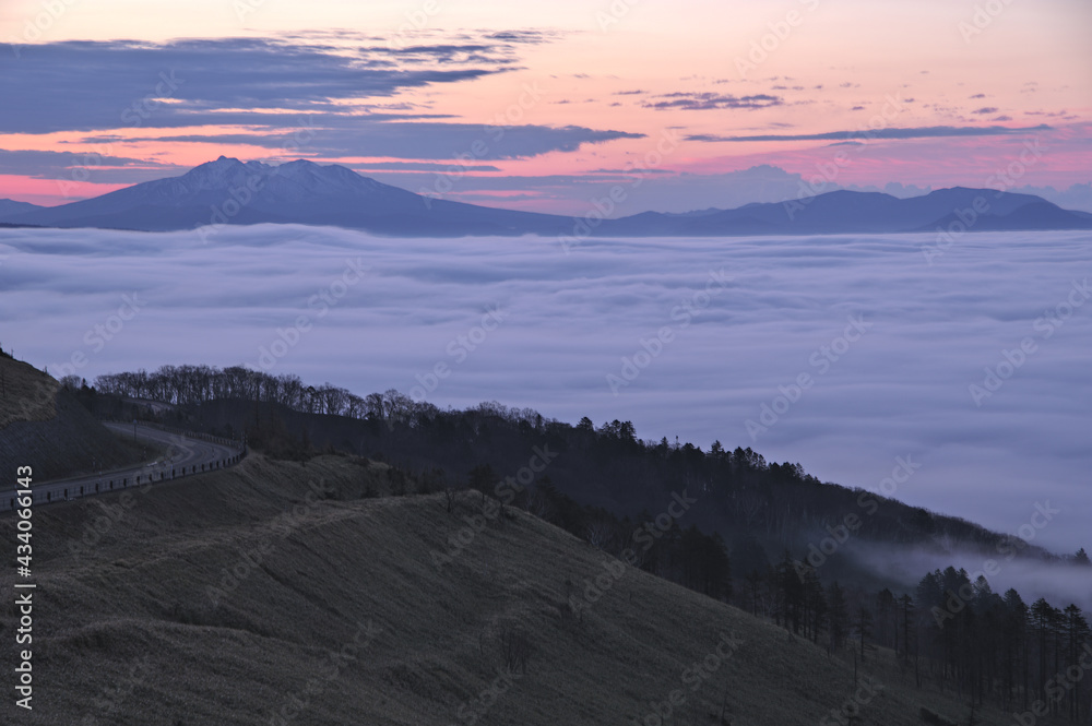雲海と遠くの山の稜線を背にした尾根を走る道。日本の北海道の美幌峠からの風景。
