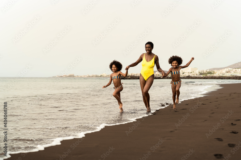 Happy Afro family having fun running on the beach during summer time - Parents love and travel lifestyle concept Happy Afro family having fun running on the beach during summer time - Parents love and travel lifestyle concept