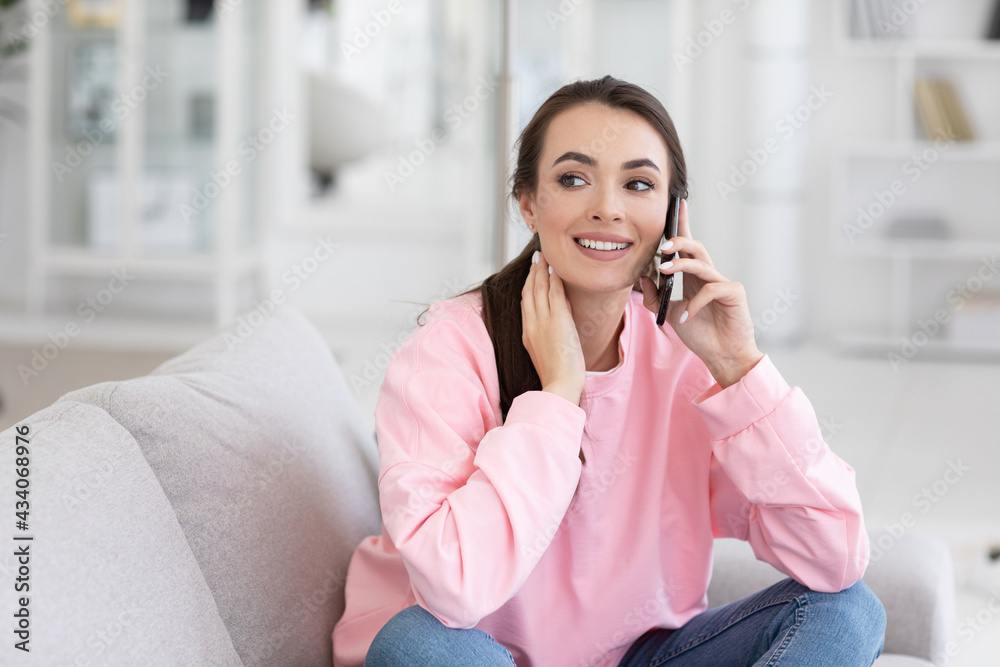 Close up portrait of beautiful calm woman talking on smartphone with friend, sitting on sofa against cozy interior. Female student posing indoors Close up portrait of beautiful calm woman talking on smartphone with friend, sitting on sofa against cozy interior. Female student posing indoors