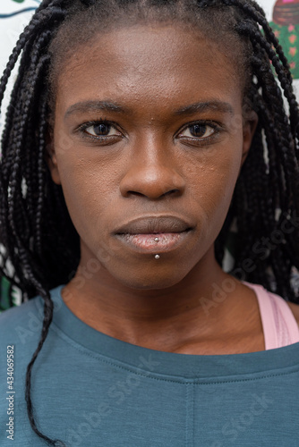 Headshot of determined African American female with black braids and piercing looking at camera