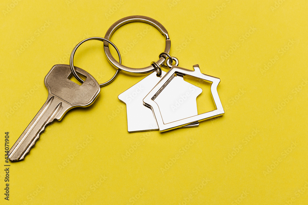 The concept of mortgage and rental housing and real estate. Mortgage credit lending. Keychain in the shape of a house with a key on a yellow background. The concept of mortgage and rental housing and real estate. Mortgage credit lending. Keychain in the shape of a house with a key on a yellow background.