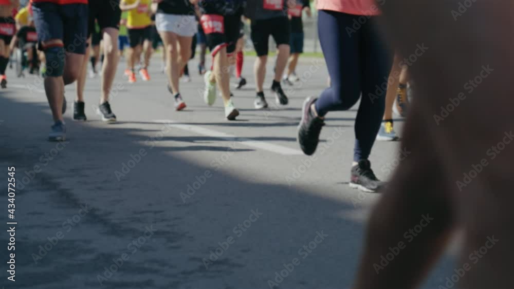 Slow motion legs of runners competing in street race. Partial view athletic people taking part in marathon. Concept of sport Slow motion legs of runners competing in street race. Partial view athletic people taking part in marathon. Concept of sport