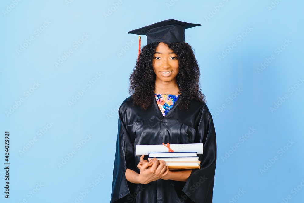 Young African-American student in bachelor robe on color background Young African-American student in bachelor robe on color background
