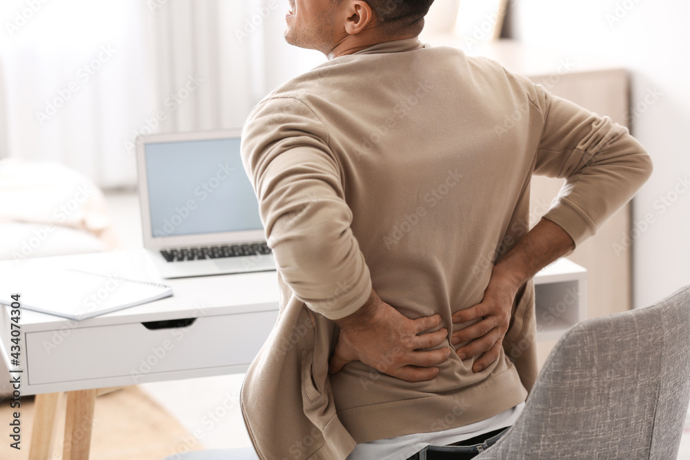 Man suffering from back pain at table, closeup. Bad posture problem Man suffering from back pain at table, closeup. Bad posture problem