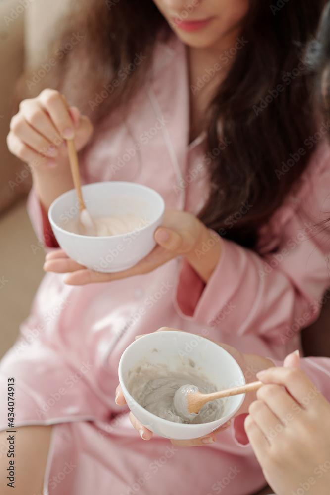 Close-up image of young women mixing powdered clay and water in bowl to applying it as face mask later Close-up image of young women mixing powdered clay and water in bowl to applying it as face mask later