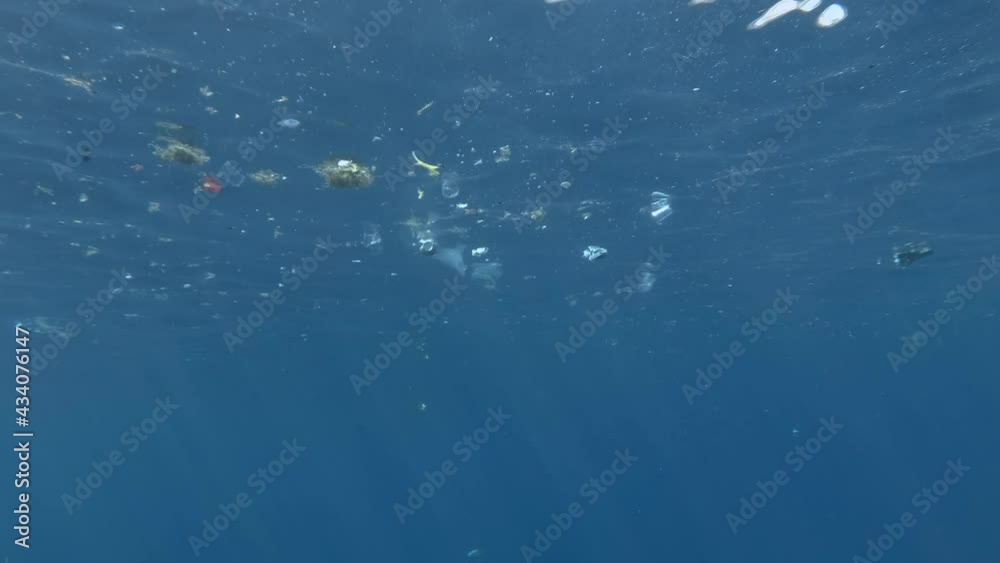 Plastic and other garbage slowly drifting on surface of the blue water approaching the coral reef. Massive polluting of the Ocean. Plastic and other garbage slowly drifting on surface of the blue water approaching the coral reef. Massive polluting of the Ocean.
