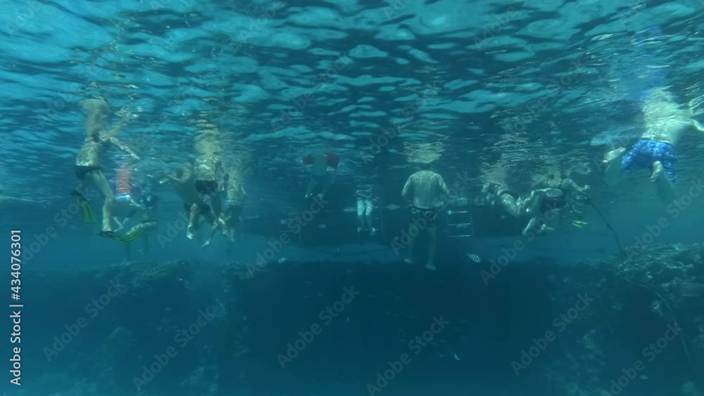 A group of tourists have fun at the hotel pier next to a coral reef in the sun. Vacationers swim in the sea next to the corals. Underwater shot A group of tourists have fun at the hotel pier next to a coral reef in the sun. Vacationers swim in the sea next to the corals. Underwater shot