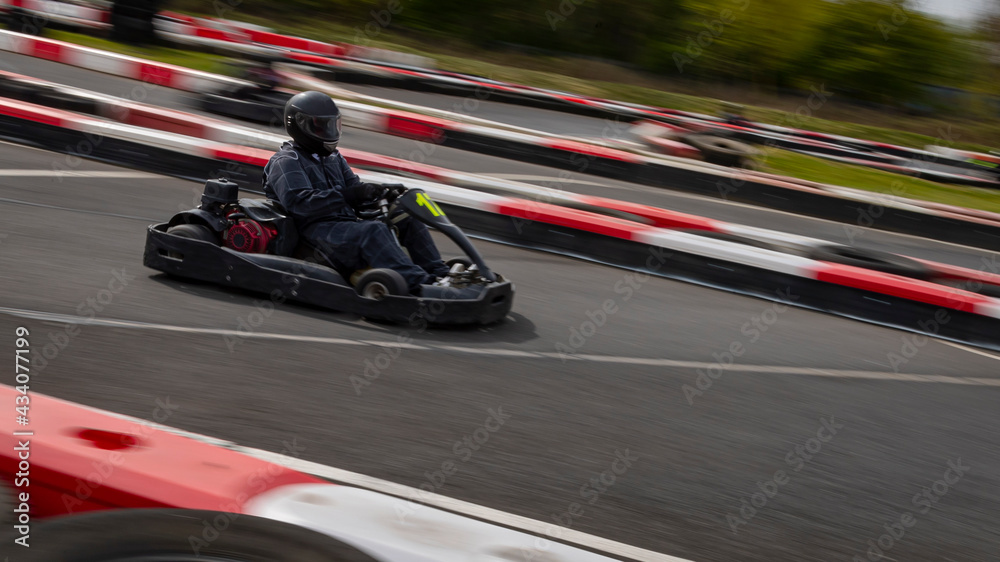 A panning shot of a racing kart as it circuits a track.