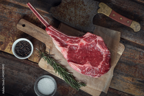 Принти на полотні Tomahawk steak, rosamarine, spices and an old meat cleaver on a wooden table