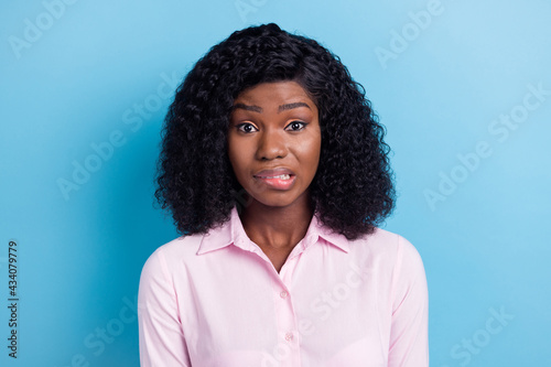 Photo of impressed guilty dark skin lady dressed pink clothes biting lip isolated blue color background