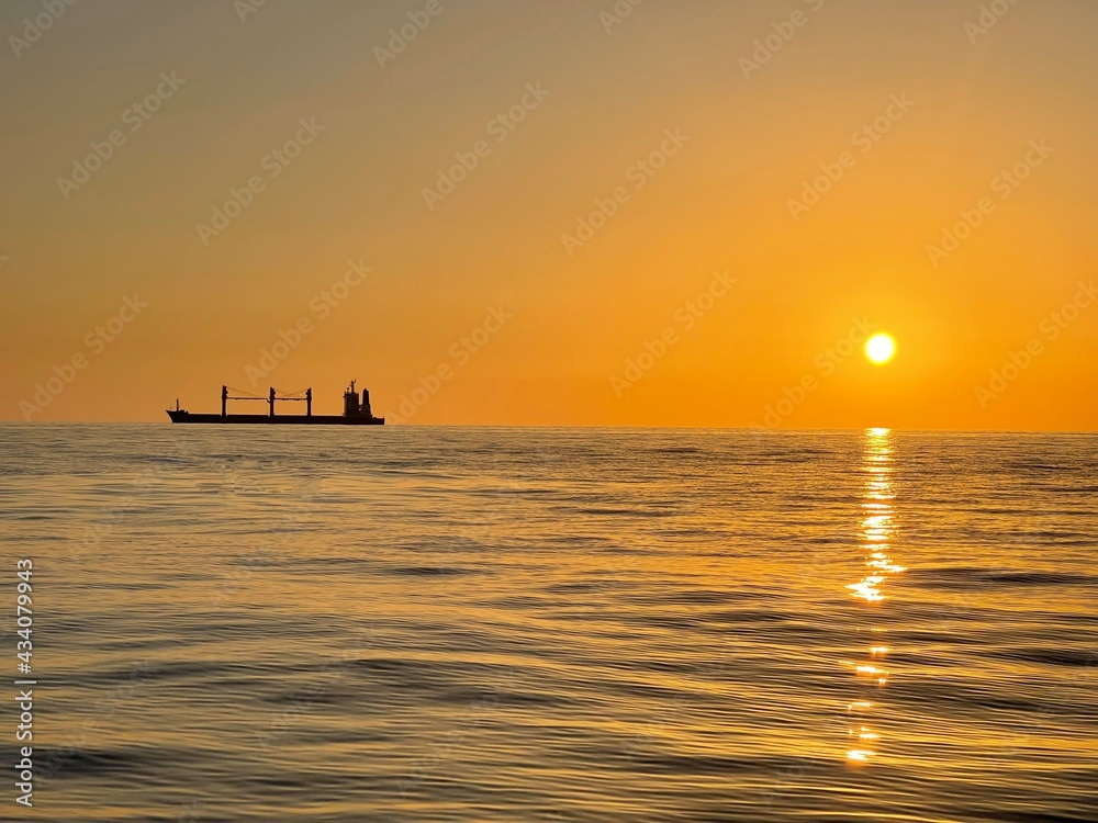 Silhouette of a freight ship on the horizon of the Mediterranean sea during sunset Silhouette of a freight ship on the horizon of the Mediterranean sea during sunset