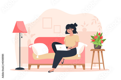 Young woman sitting on sofa and working on laptop from home