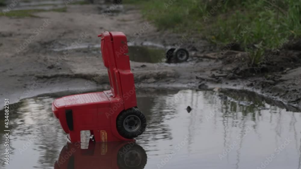 a broken toy car is lying in a puddle.