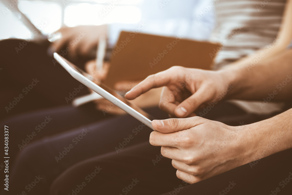 Group of casual dressed business people working at meeting or conference, close-up of hands. Businessman using tablet computer. Teamwork or coaching concept Group of casual dressed business people working at meeting or conference, close-up of hands. Businessman using tablet computer. Teamwork or coaching concept