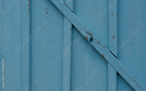 Old cracked boards of various sizes, nailed in different directions, painted light blue.